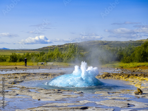exploding Geyser with a man with a tablet taking a picture in the background