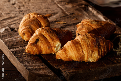 Freshly baked French croissants with cappuccino milk on a dark background with copy space.