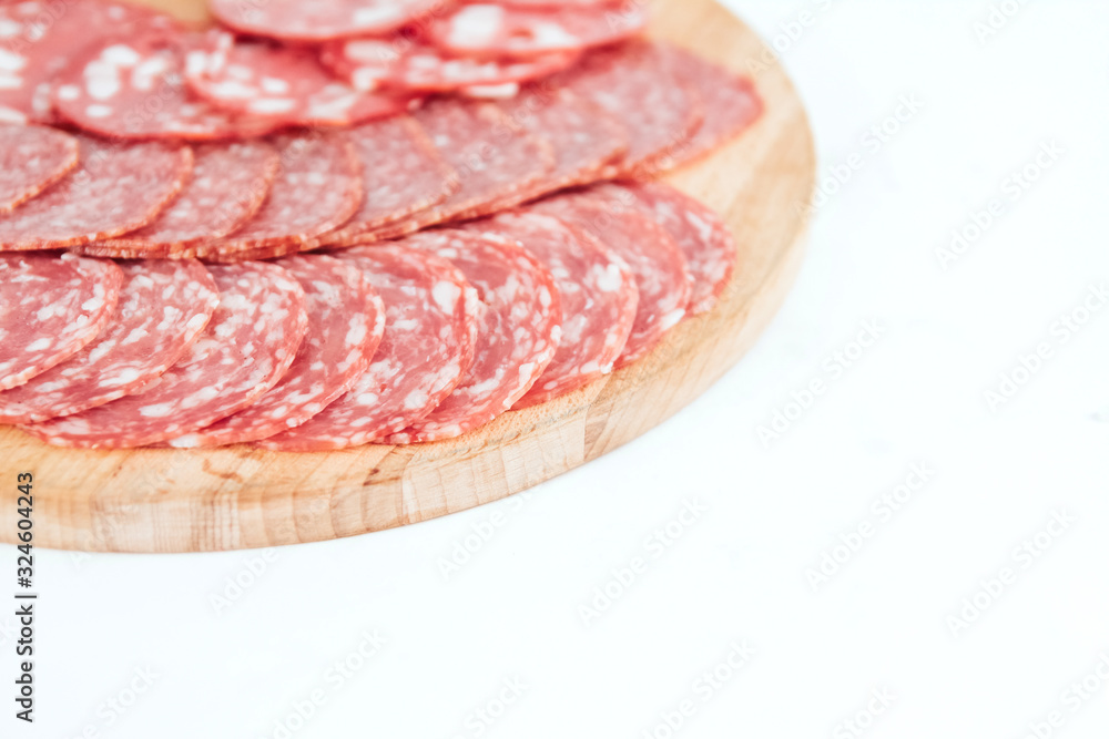 Thin slices of sausage on a wooden board copy space. Sliced ​​Salami.