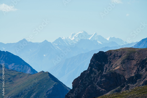 Awesome aerial view to great snowy mountains behind deep gorge. Wonderful mountain landscape with giant rockies and deep abyss. Highland scenery with huge glacier in distance. Big rocks and precipice.