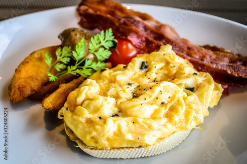 truffle egg with bacon strips and potato wedges on white plate