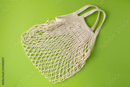 Mesh shopping bag at green background. Zero waste concept.