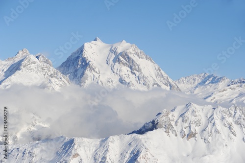 Snowy mountain peak with clouds and fog in ski resort Courchevel French Alps.