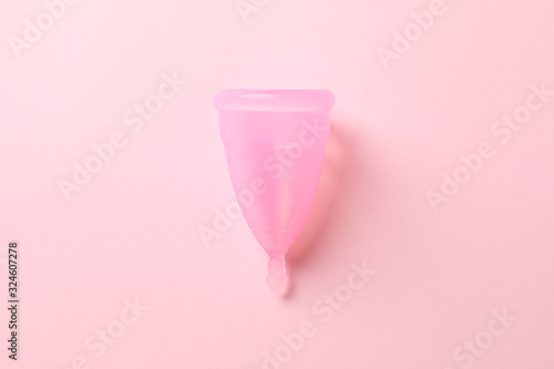 Menstrual cup on pink background, close up and space for text