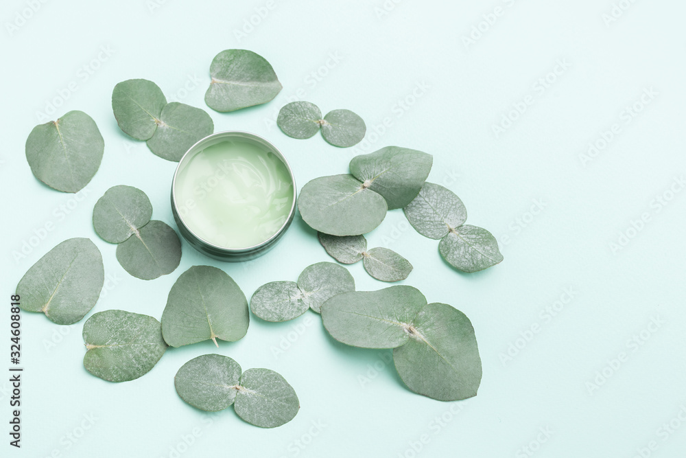 Flat lay composition of eucalyptus cream in jar on blue paper background with foliage on. Top view, flat lay, mock up with copy space Flat lay composition of eucalyptus cream in jar on blue paper background with foliage on. Top view, flat lay, mock up with copy space