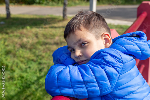 Boy walks in the park and stands in the water edge fence with funny look.