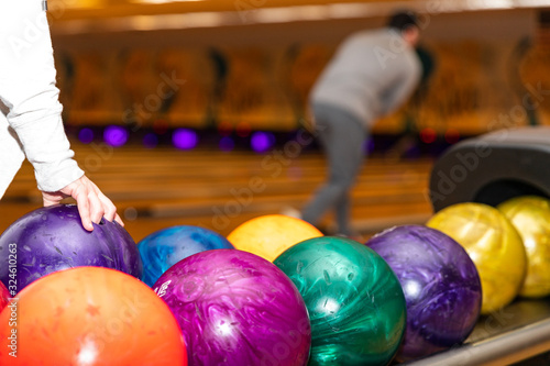 Hand picking up bowling ball at bowling alley.