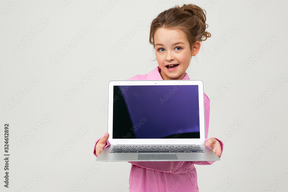 attractive charming young girl in a pink suit shows a laptop screen with a layout on a white background attractive charming young girl in a pink suit shows a laptop screen with a layout on a white background