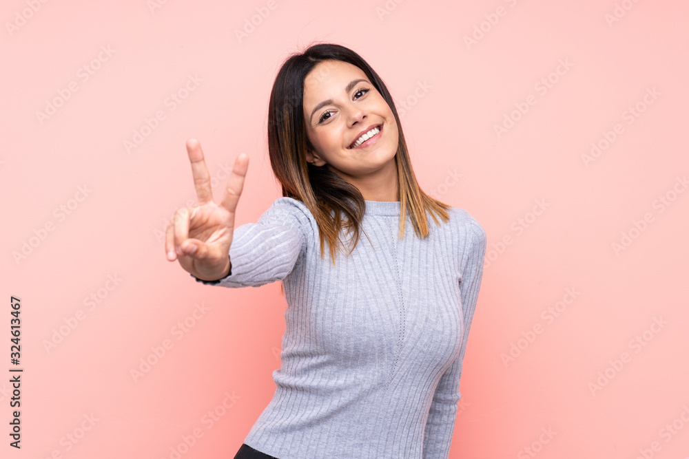 Woman over isolated pink background smiling and showing victory sign Woman over isolated pink background smiling and showing victory sign