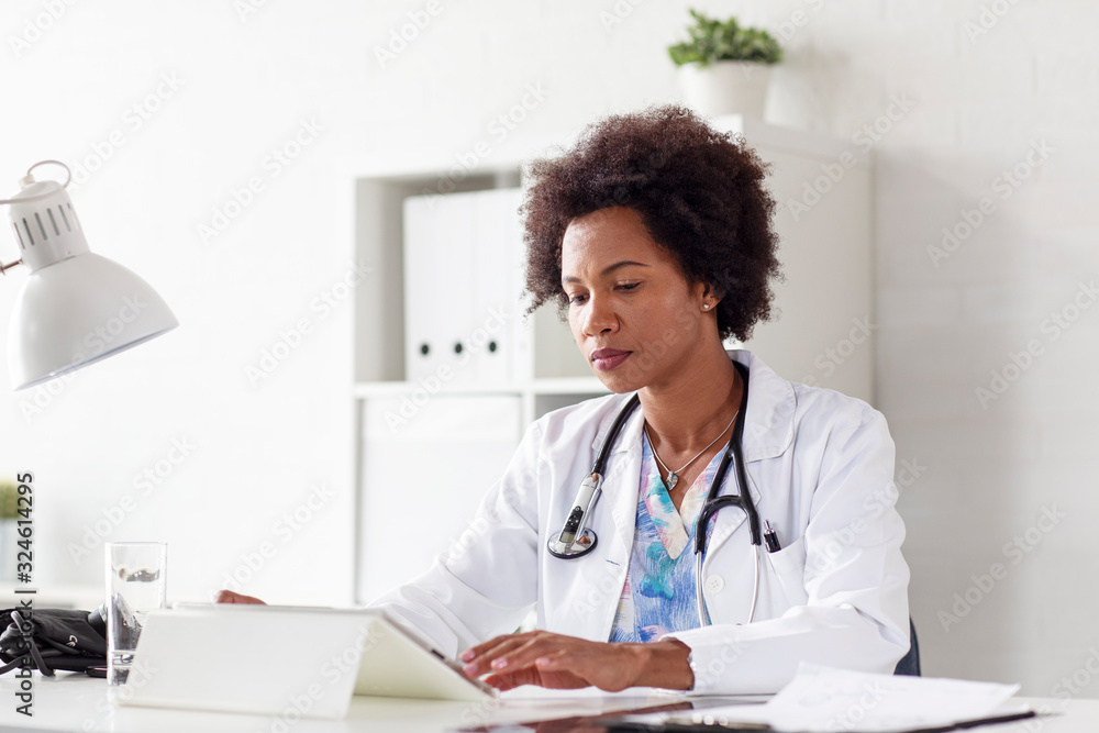 Doctor woman typing on tablet on desk in her office at hospital Doctor woman typing on tablet on desk in her office at hospital