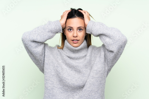 Woman wearing a sweater over isolated green background with surprise facial expression