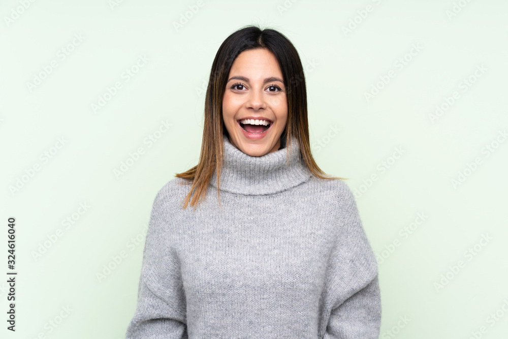 Woman wearing a sweater over isolated green background with surprise facial expression Woman wearing a sweater over isolated green background with surprise facial expression
