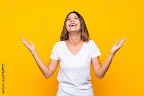 Young woman over isolated yellow background smiling a lot