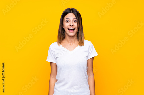 Young woman over isolated yellow background with surprise facial expression