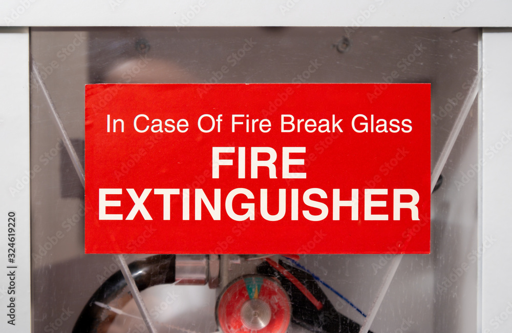 Sticker on fire extinguisher in hallway. Close up. Red label