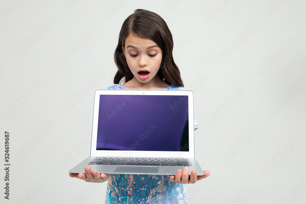 Naklejka premium surprised teenager girl holding a laptop with a mockup for inserting a website on a white studio background