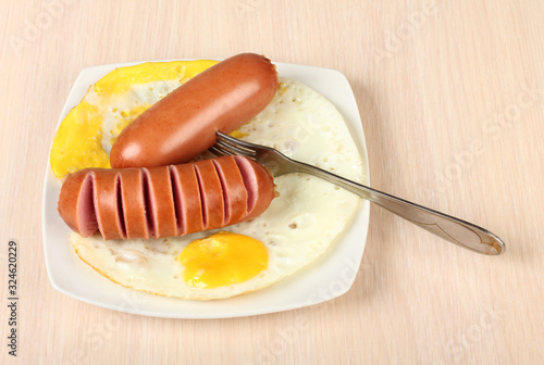 Fried sausage and fried eggs on a ceramic plate photo