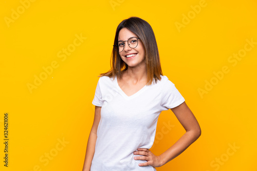 Young woman over isolated yellow background with glasses and happy