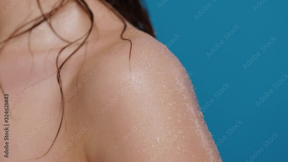 close-up of water splashes falling down from wet woman shoulder isolated on blue close-up of water splashes falling down from wet woman shoulder isolated on blue