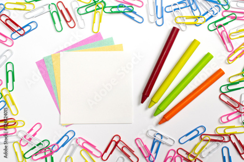 Colorful paper clips, note papers and wax pencils in the centre of composition isolated on white.