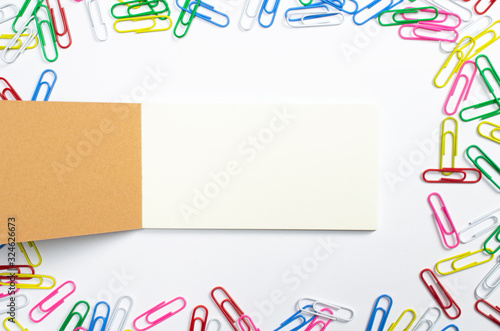 Blank opened notebook diary, in the centre and colorful paper pins arround isolated on white.