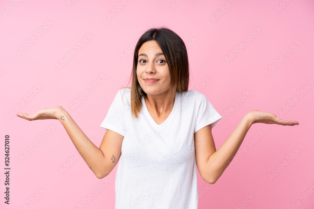 Young woman over isolated pink background having doubts while raising hands Young woman over isolated pink background having doubts while raising hands