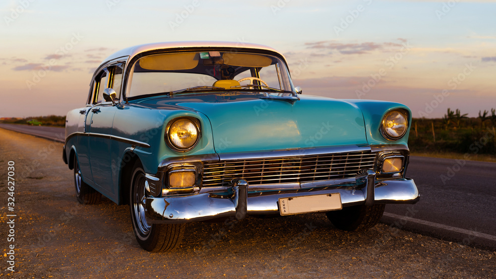 old vintage baby blue classic car with white top at sunset, cuba