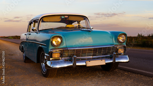 old vintage baby blue classic car with white top at sunset, cuba