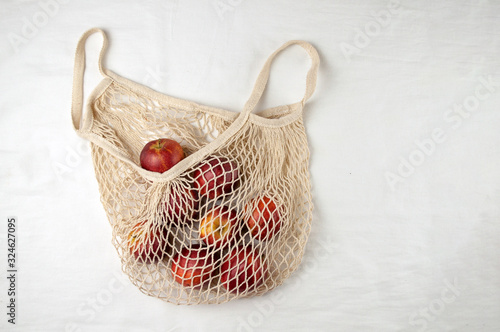 Mesh shopping bag with apples on a white background. the view from the top. Zero waste, plastic-free concept. Healthy clean nutrition and detoxification. Summer fruits. Flat lay Copy space