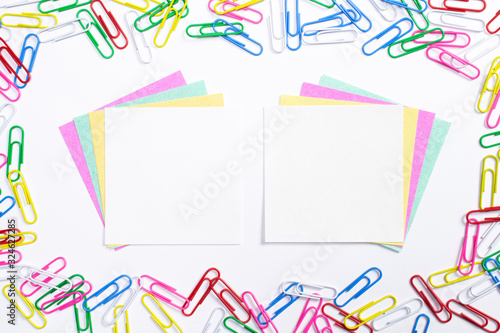 Colorful paper clips and note papers in the centre of composition isolated on white.