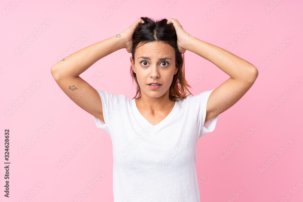 Young woman over isolated pink background frustrated and takes hands on head Young woman over isolated pink background frustrated and takes hands on head