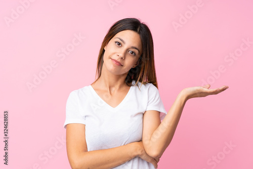 Young woman over isolated pink background unhappy for not understand something