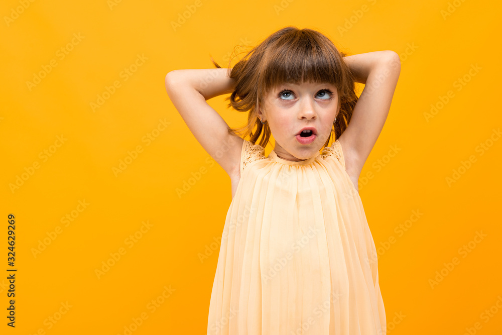 Beautiful little girl in dress isolated on yellow or orange background Beautiful little girl in dress isolated on yellow or orange background