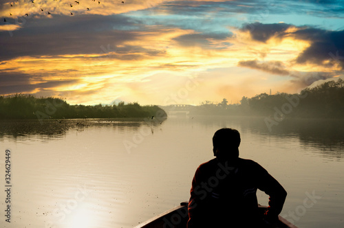 silhouette of boatsman rowing out into the yamuna ganga river in the morning photo