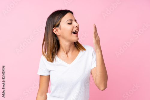 Young woman over isolated pink background yawning and covering wide open mouth with hand