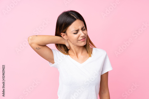 Young woman over isolated pink background with neckache