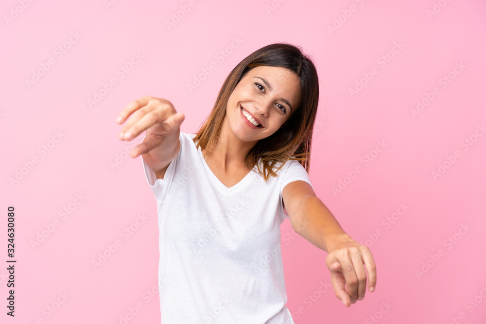 Young woman over isolated pink background points finger at you while smiling Young woman over isolated pink background points finger at you while smiling