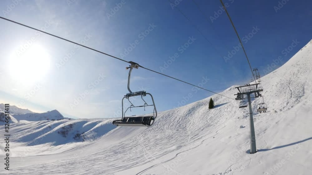 riding on the chairlift above the slopes in the ski area on a beautiful sunny day, blue sky