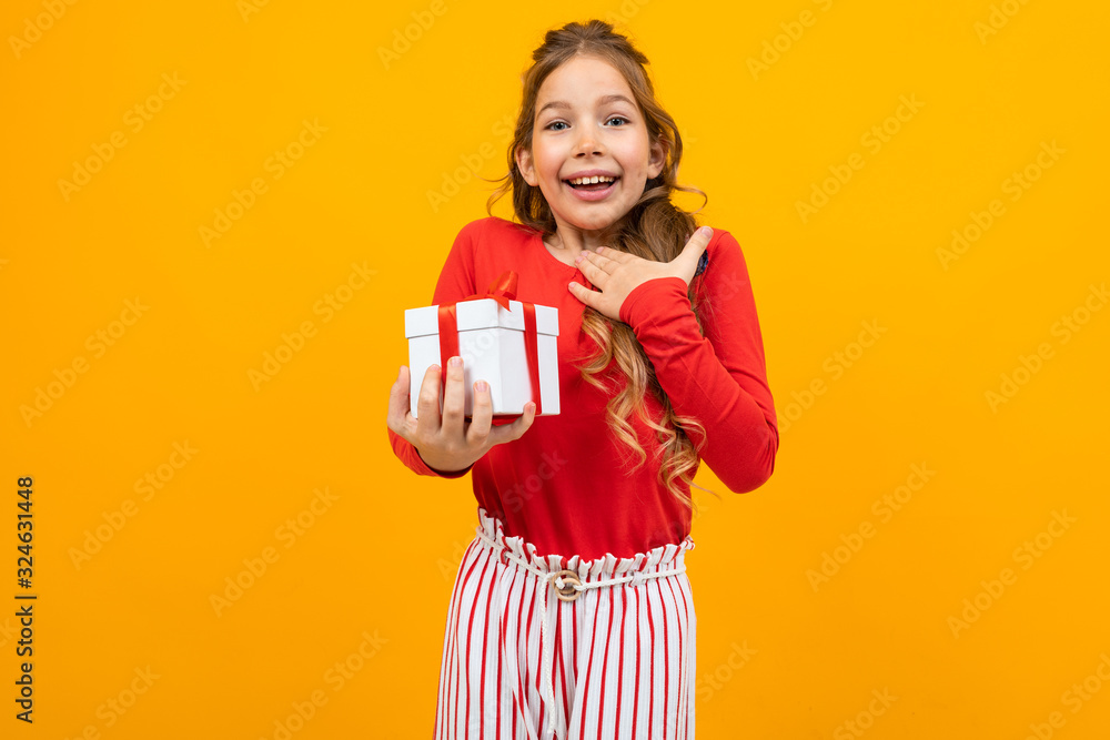 surprised smiling beautiful girl with a gift box on a yellow background with copy space surprised smiling beautiful girl with a gift box on a yellow background with copy space