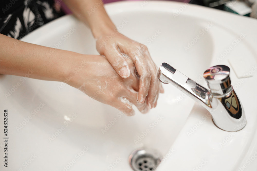 women washing hands with sanitizer soap and water after using a public ...