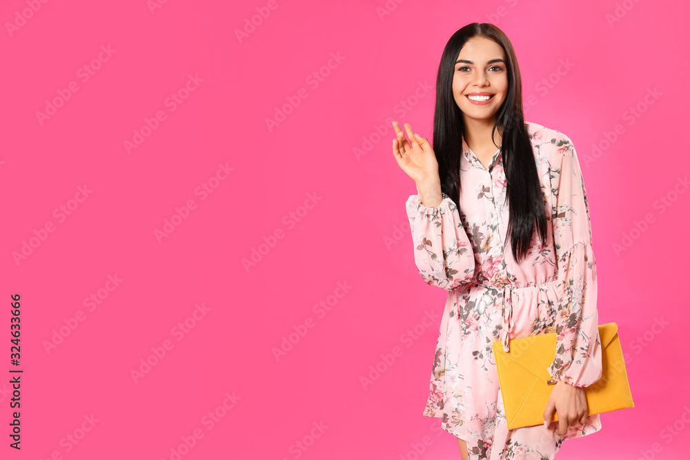 Young woman wearing floral print dress with elegant clutch on pink background. Space for text Young woman wearing floral print dress with elegant clutch on pink background. Space for text
