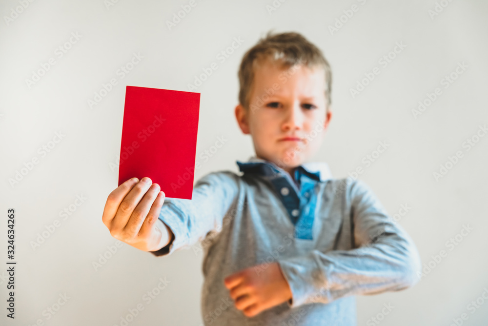 Angry face child showing a red card as a warning, stop bullying concept, blank background. Angry face child showing a red card as a warning, stop bullying concept, blank background.