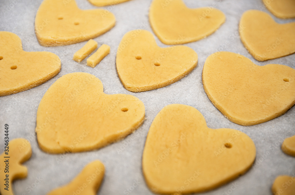 Cookies made from dough in the shape of heart lies on the baking sheet before baking