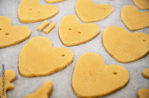 Cookies made from dough in the shape of heart lies on the baking sheet before baking