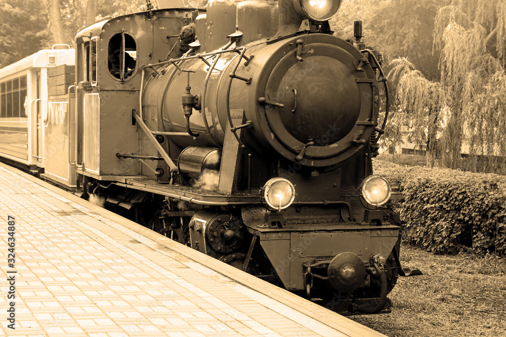 Obraz premium Old steam locomotive. Old vintage steam-powered train rides on rails.