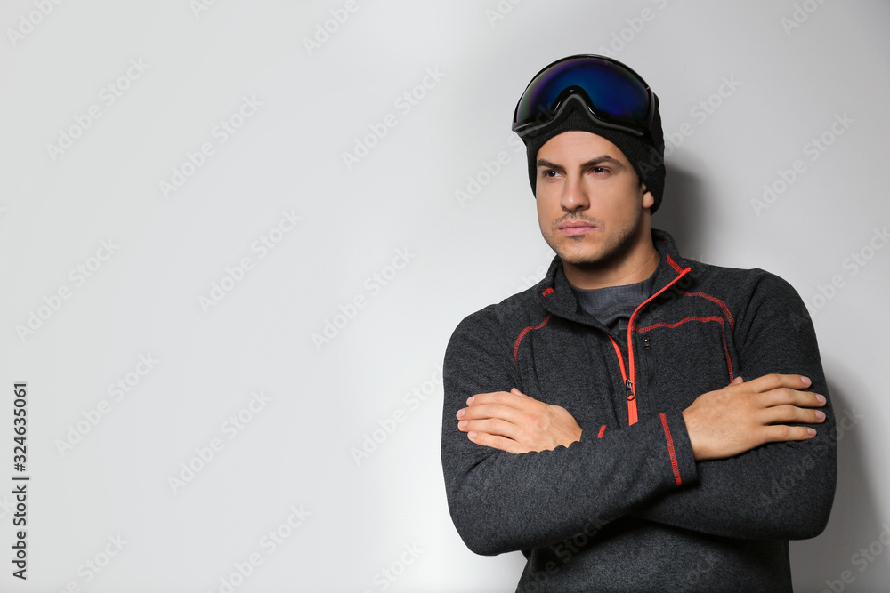 Man wearing fleece jacket and goggles on light grey background, space for text. Winter sport clothes Man wearing fleece jacket and goggles on light grey background, space for text. Winter sport clothes