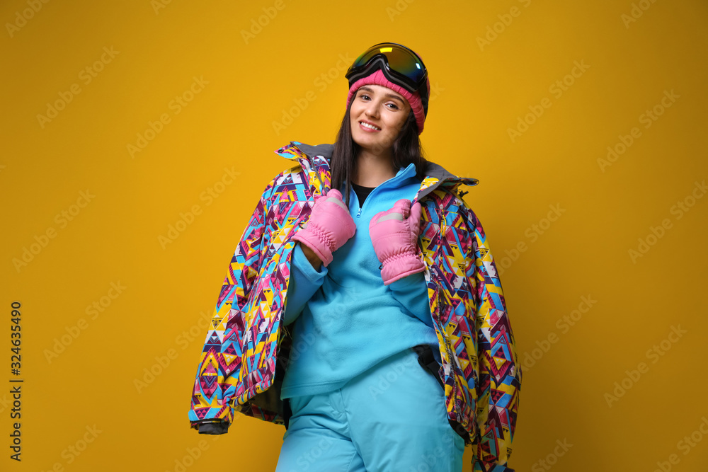 Woman wearing stylish winter sport clothes on yellow background, low angle view