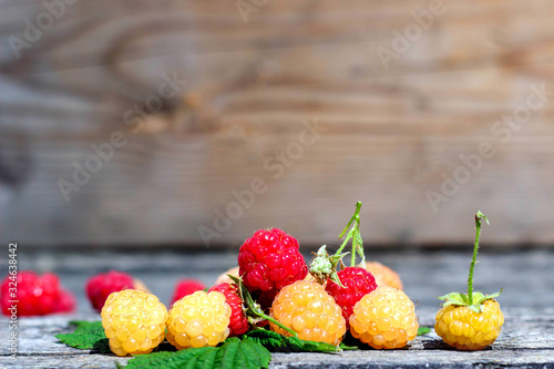 Ripe sweet raspberries on the wooden table in summer time.