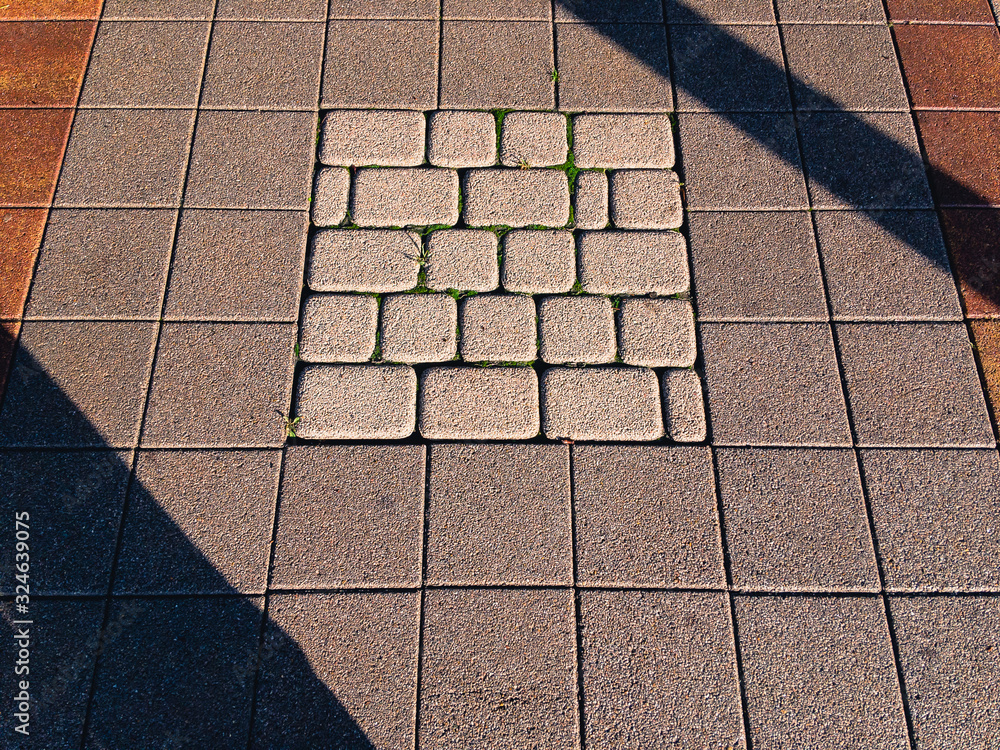 Fototapeta premium Paving slabs on a footpath in the city on a sunny morning with a shadow from the trees.
