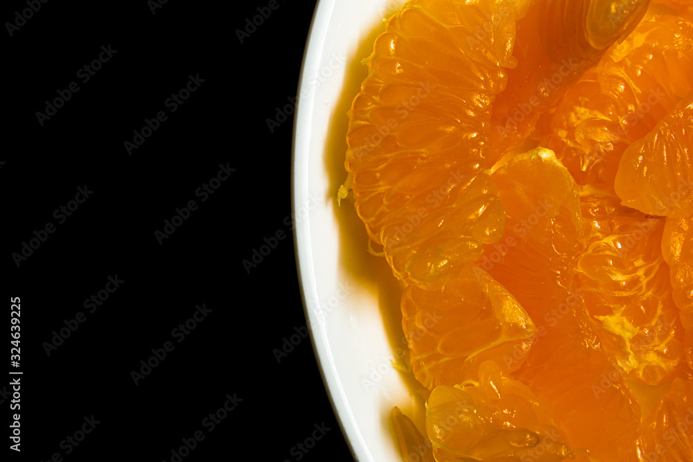 Peeled orange placed in a plate against dark background. Use for fruit concept. Peeled orange placed in a plate against dark background. Use for fruit concept.